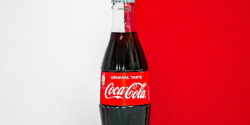 A  bottle of Coca-Cola, against a red and white background