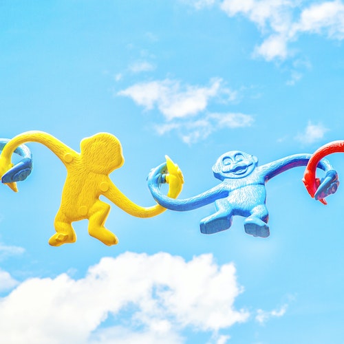 Three primary-color plastic monkeys, held aloft to the sky, holding hands, full of joy